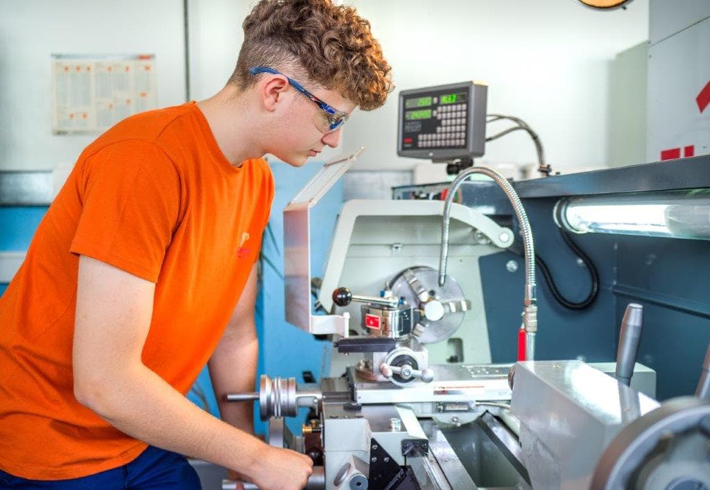 Lehrling arbeitet konzentriert an der Drehmaschine