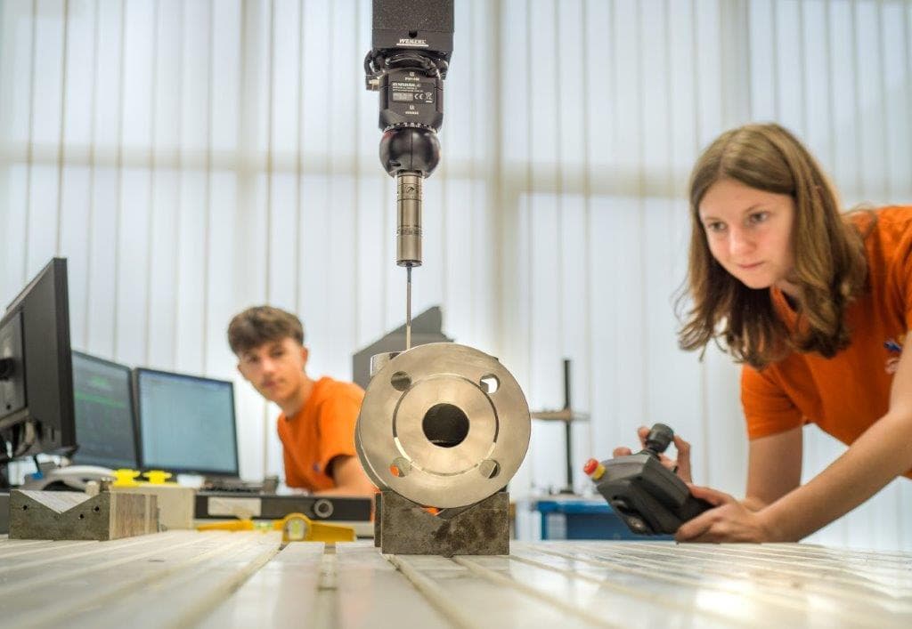 Zwei Lehrlinge messen ein Ventilgehäuse an der Fräsmaschine
